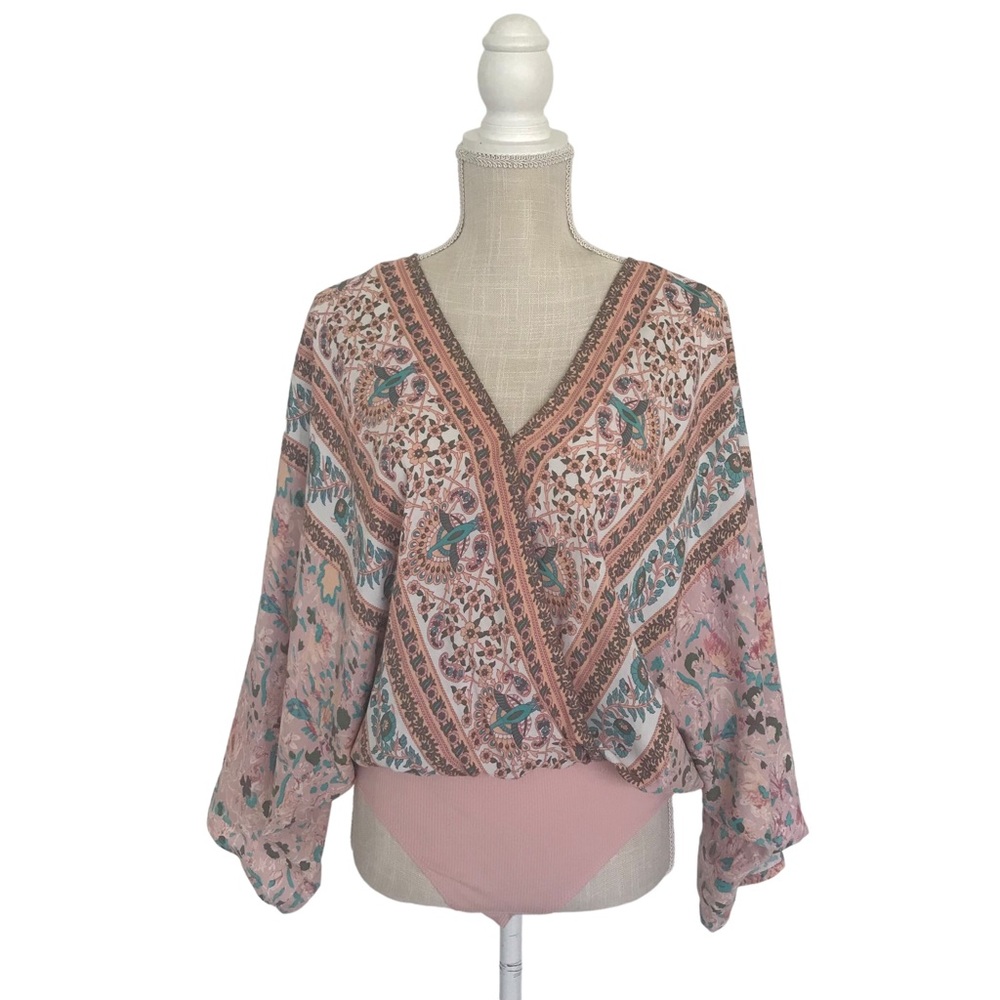 A pastel colored bodysuit with flower prints in size small.
